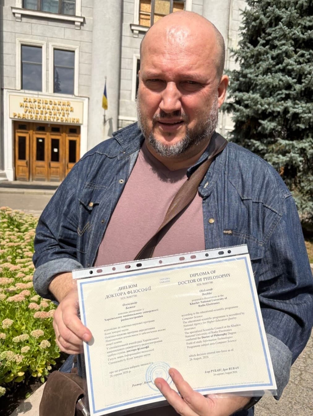 Олександр Божко з дипломом доктора філософії біля головного корпусу ХНУРЕ